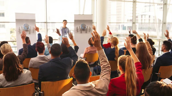 Salle de formation moderne avec groupe d'adultes assis face à une formatrice debout devant tableau blanc